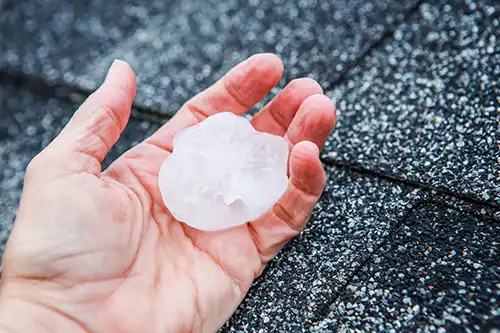 BAM Roofing & Construction—a hand holding a golf ball-sized hailstone after a storm in Central IL.
