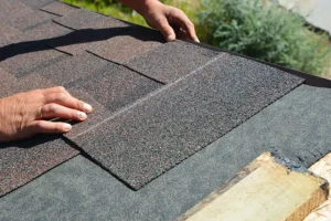 BAM Roofing & Construction—A professional roofer’s hands install asphalt shingles on a home in Central IL.