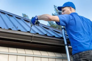 BAM Roofing & Construction—A worker in a blue uniform installing a metal roof on a home in Central IL.