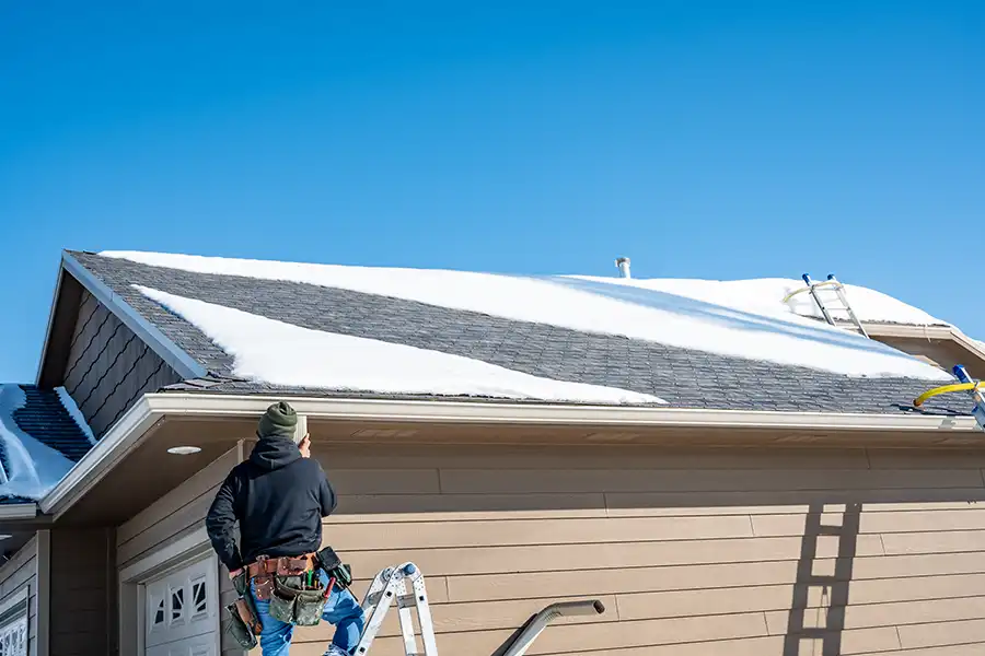 BAM Roofing & Construction—A roofer inspecting the roof of a home in Central IL for leaks during the winter season.