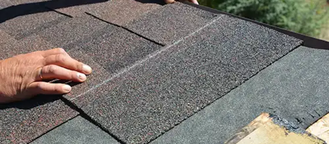 BAM Roofing & Construction—A professional roofer’s hands install asphalt shingles on a home in Central IL.